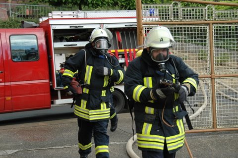 Feuerwehrleute mit Atemschutz vor dem Einsatzfahrzeug